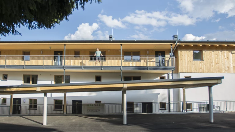 Person steht am Aufgang zu den einzelnen Wohnungen im Wohnpark Forstau