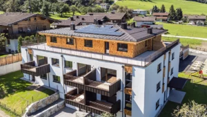 Vogelperspektive der Wohnanlage in Niedernsill mit Sicht auf die Holzschindelfassade und Photovoltaikanlage am Dach