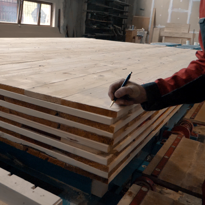 Mitarbeiter in der Halle mit Bleistift an einer Massivholzwand