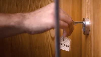 Person die einen Wohnungsschlüssel in die Wohnungstür steckt